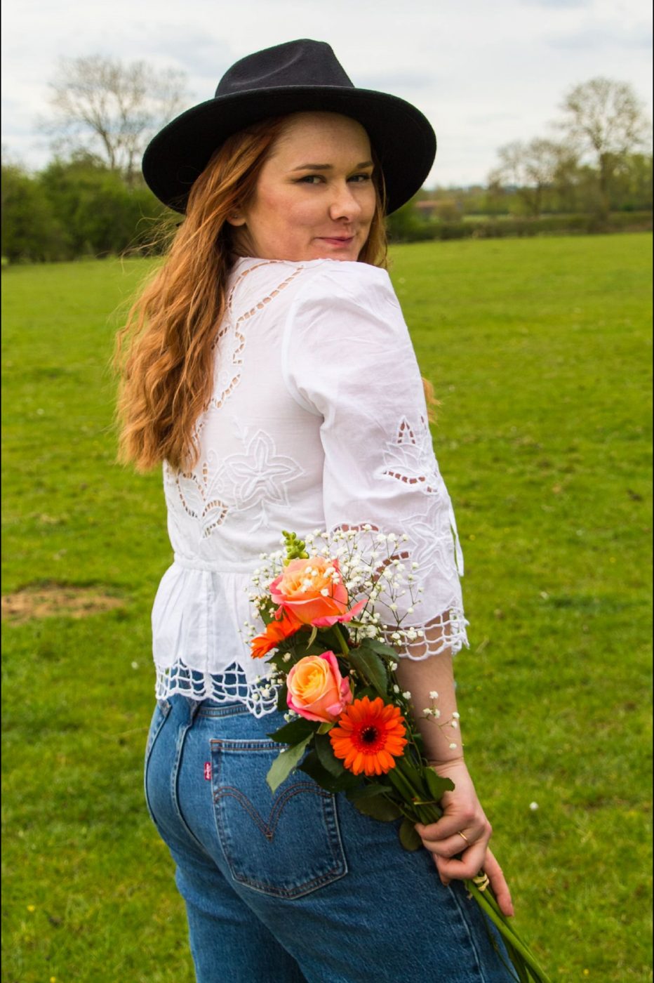 Hannah Collins, wedding celebrant, in a field holding a bouquet